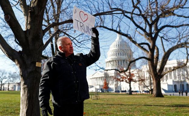 Un hombre con una pancarta pro-Trump frente al Capitolio.