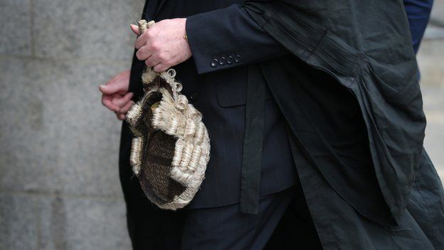 A barrister holds his wig as he arrives at The Old Bailey on 27 July 2015