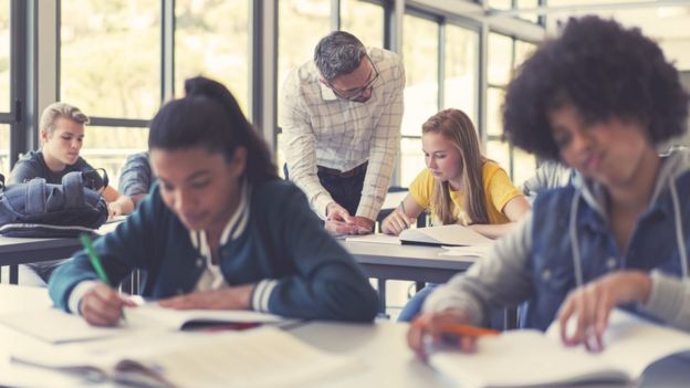 Estudiantes en un aula con libros.