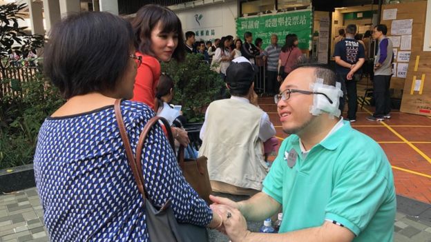 Andrew Chiu, candidato nas eleições do conselho distrital de Hong Kong em novembro de 2019, sentou-se do lado de fora de uma estação de votação conversando com os eleitores