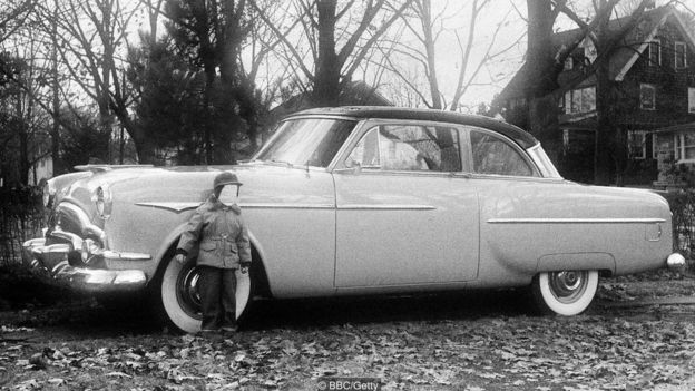 Niño frente a un automóvil.