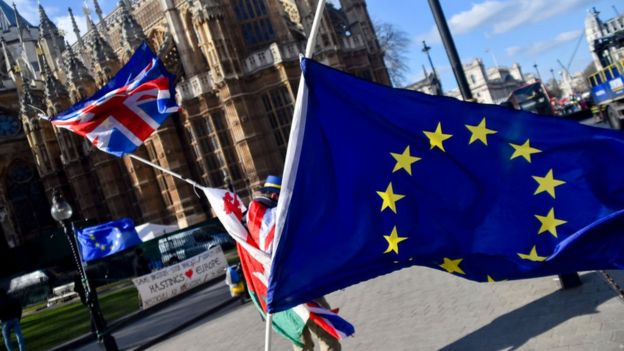 Un manifestante sostiene las banderas de Reino Unido y la UE frente al Parlamento británico.