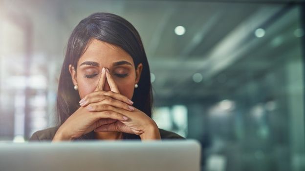 Mujer estresada delante de su laptop