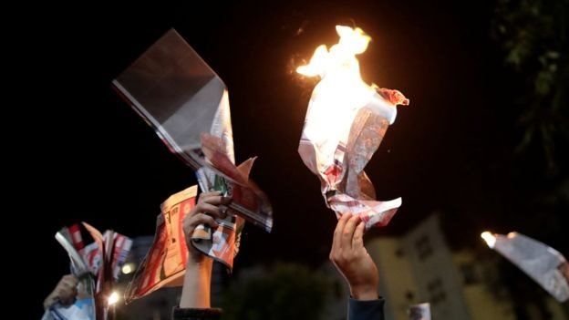 Manifestantes erguem papeis em chamas