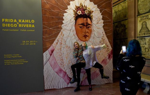 Dos jóvenes posan ante el carte de la exposición "Frida Kahlo y Diego Rivera: contexto polaco" del Centro Cultural ZAMEK de Poznań, Polonia.
