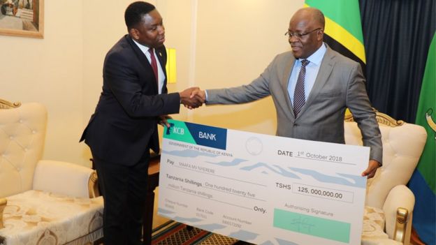 Rais Magufuli akipokea mfano wa hundi yenye thamani ya Sh125m kutoka kwa balozi wa Kenya Dkt. Dan Kazungu