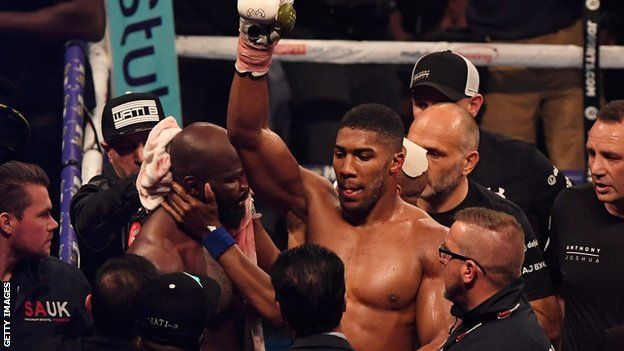 Anthony Joshua's arm is lifted in triumph after Carlos Takam is stopped in Cardiff
