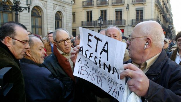 Manifestante con cartel que dice "ETA asesina inmigrantes, !Basta ya!"