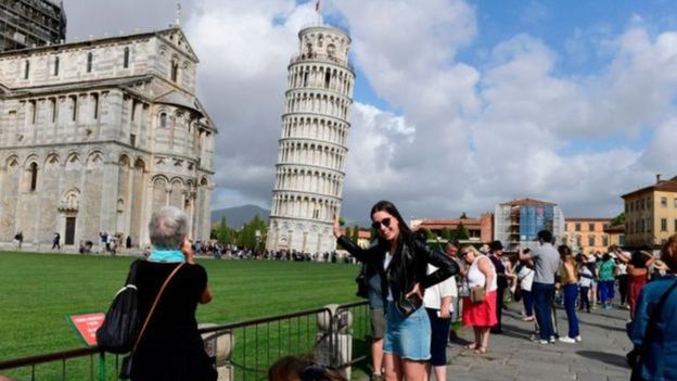 Mulher tirando foto com a torre de Pisa