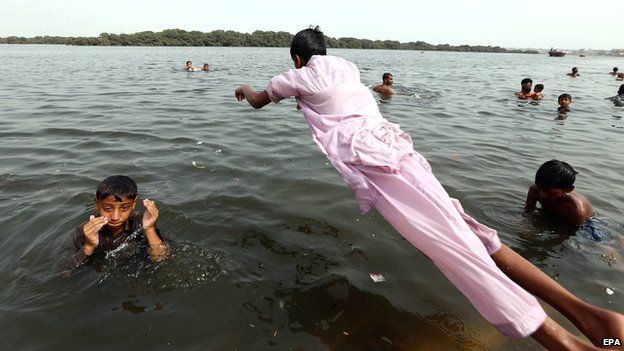 People jump in the water to cool off in Karachi