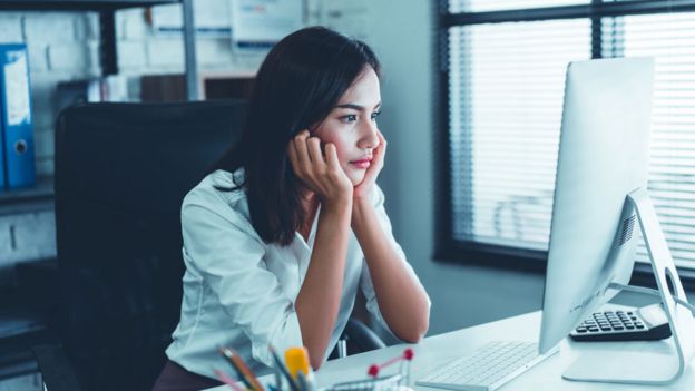 Mujer sentada frente a una computadora.