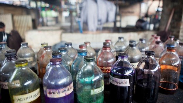 A collection of glass bottles containing dyes to be used for staining wool at a textile factory in Nepal