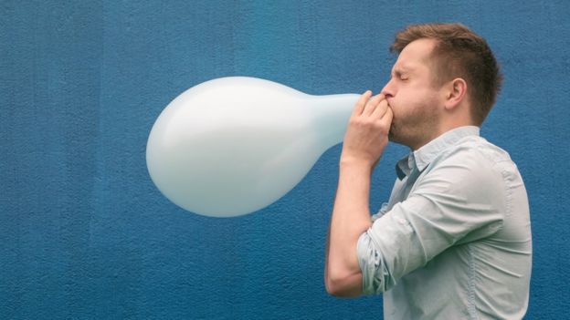 Hombre inflando un globo.