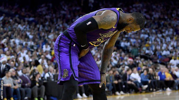 LeBron James bends over in pain after straining his groin against the Golden State Warriors