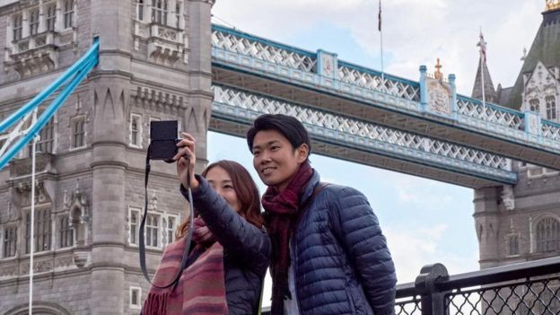 Casal jovem tira foto em frente à Tower Bridge, em Londres