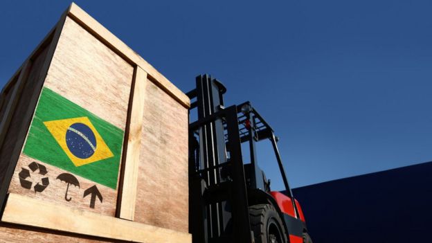 Trator carrega caixa com bandeira do Brasil