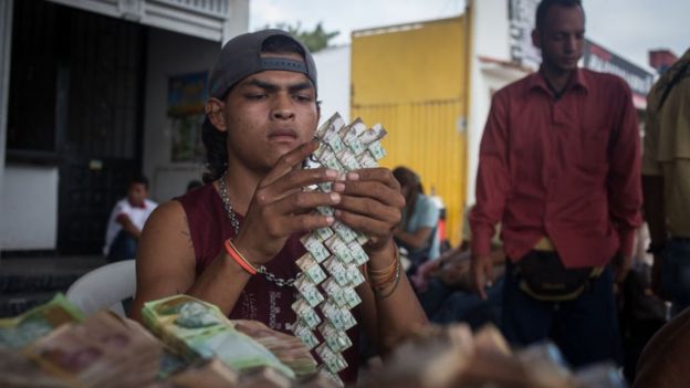 Hombre haciendo manualidades con billetes venezolanos