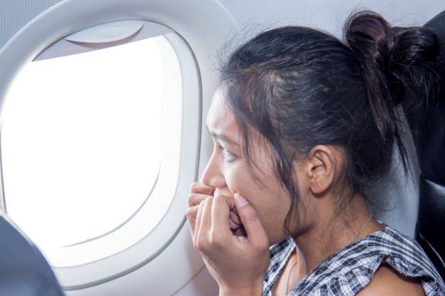 Mujer con cara de miedo en un avión