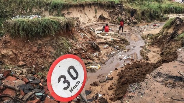 Pemba residents stand by a road partially destroyed by heavy flooding