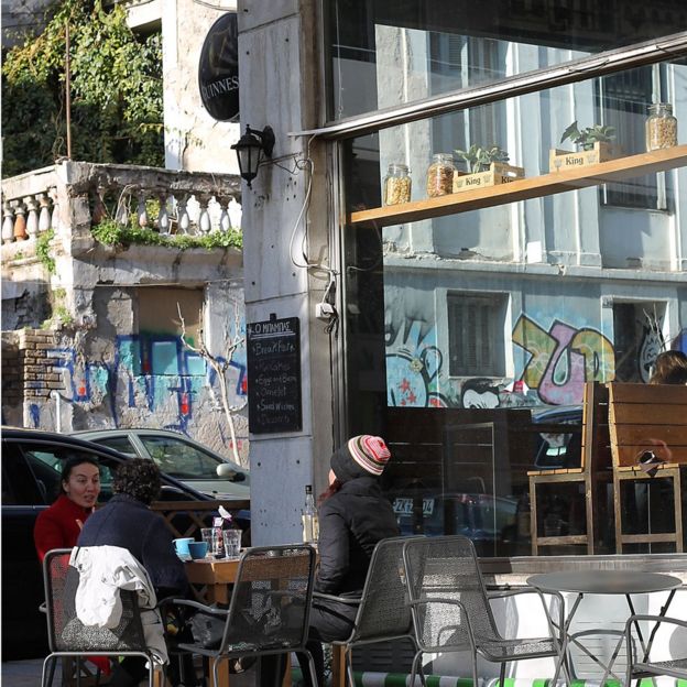 Women on a cafe terrace, next to crumbling and dilapidated buildings