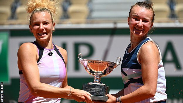 Katerina Siniakova and Barbora Krejcikova jump in the air with their French Open trophy