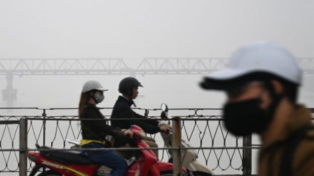 Motorists wearing face masks ride o&shy;n the Long Bien bridge amidst a blanket of smog over Hanoi o&shy;n March 28, 2018