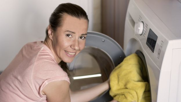 Una mujer metiendo ropa en una lavadora