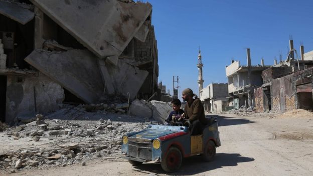 A Syrian man drives a home-made toy car through Beit Naim in the Eastern Ghouta on 7 March 2017