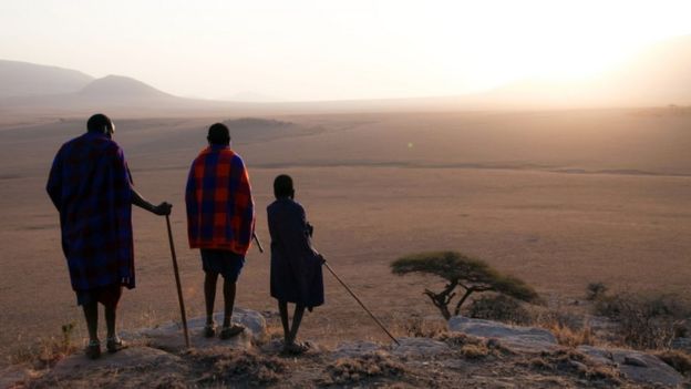 Maasai cattle herder, Parakapooni, and his brother and son look over the brown plains of the Serengeti, Tanzania.