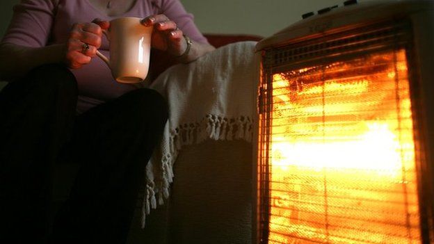Pensioner in front of heater