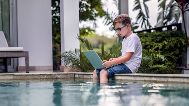 Niño con una laptop en una piscina