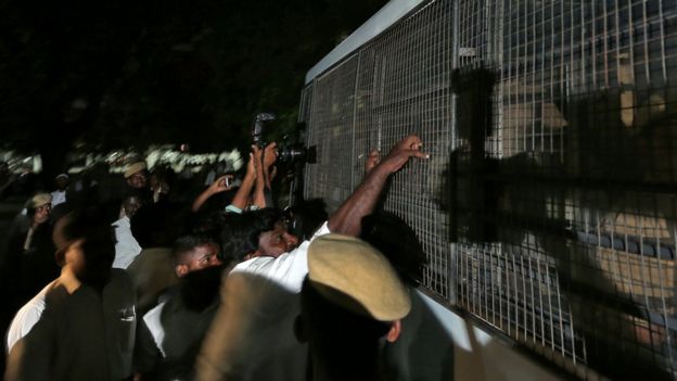 A lawyer attempts to pull the fenced window of a police vehicle carrying men accused of raping a girl inside the high court premises in Chennai, India, July 17, 2018