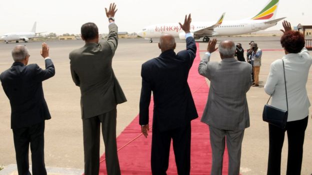 Dignitaries waving farewell to aeroplane