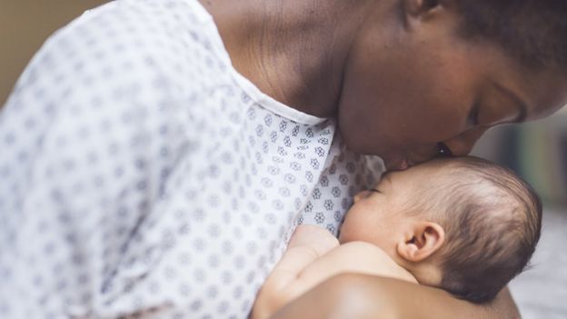 Mãe beija testa de bebê recém-nascido