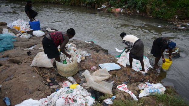 Women wash used plastic bags for re-use at the shores of a river in Nairobi (24 June 2014)