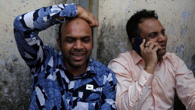 Two men grieve outside Dhaka Medical College