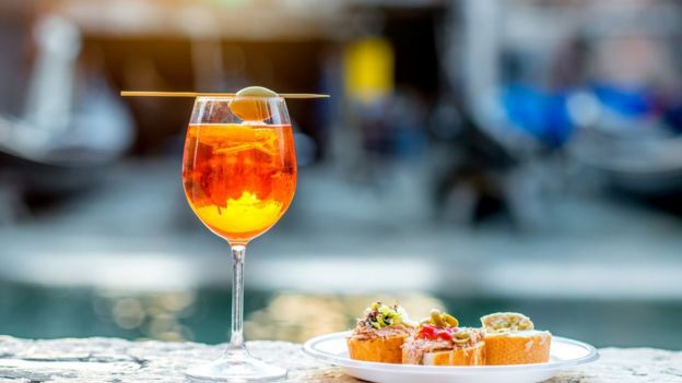 Una copa de spritz junto a algo para picar