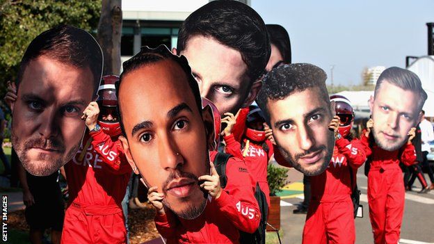 Albert Park workers hold giant cardboard cutouts of F1 drivers' faces