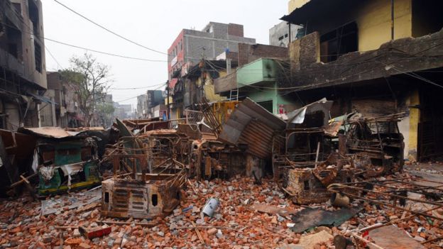 Police walk on debris at a riot affected area of Shivpuri following the Citizenship Amendment Act (CAA) clashes in Delhi