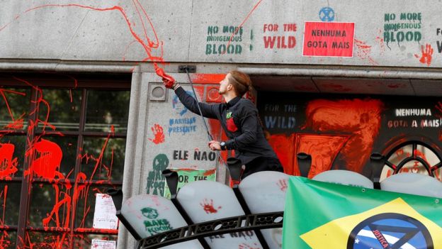 Um ativista joga tinta vermelha na fachada da Embaixada brasileira durante um protesto do Extinction Rebellion na Embaixada brasileira em Londres em 13 de agosto de 2019