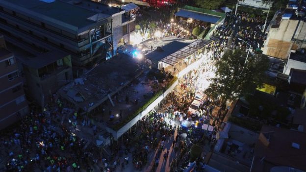 Rescuers use searchlights to remove rubble and debris from a flattened building in search of survivors after a powerful quake in Mexico City on September 19, 2017.