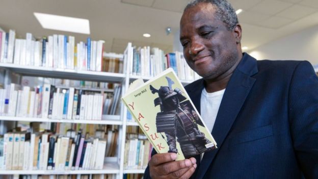 O escritor franco-marfinense Serge Bile lê uma cópia de seu último livro "Yasuke" na biblioteca do Centro Cultural Francês (CCF) em Abidjan em 28 de março de 2018.