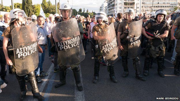 Riot policemen stand between anti-austerity and pro-euro protesters in front of the Greek parliament building on 22 June 2015.