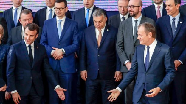 French President Emmanuel Macron and European Council President Donald Tusk gesture for Theresa May to join a photo of EU leaders at the European Council Summit in Brussels, Belgium in March 2019