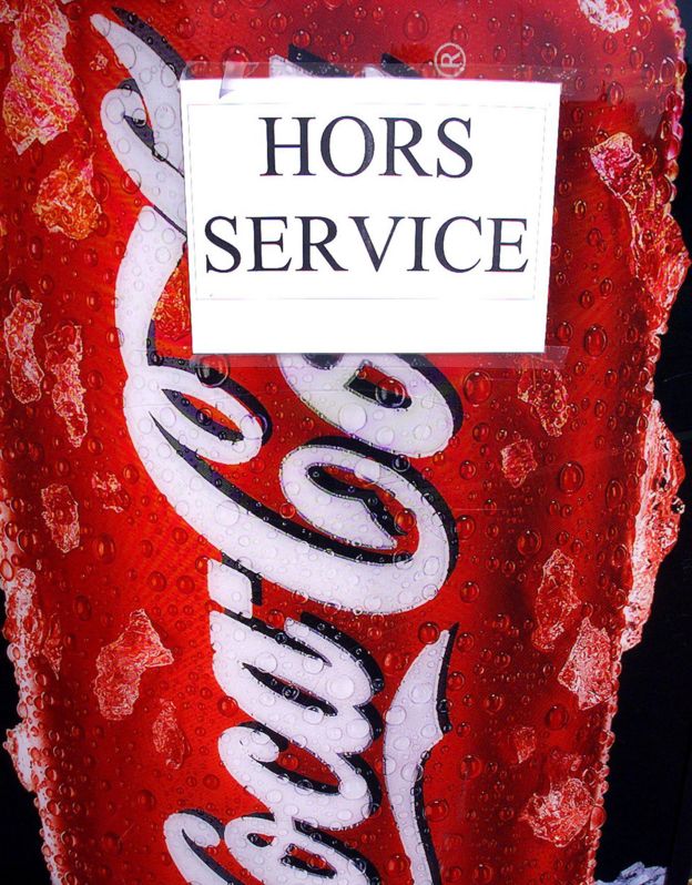 Máquina expendedora de Coca-Cola con cartel que dice 