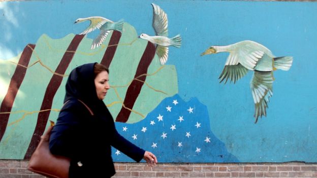 Mujer iraní caminando con un mural de fondo sobre el pacto nuclear.