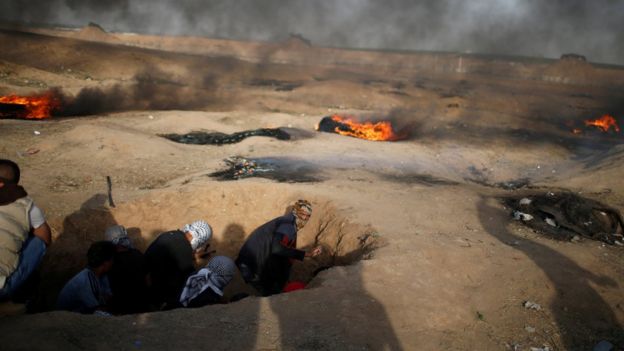 Manifestantes entre las llamas en las protestas en la frontera de Gaza con Israel.