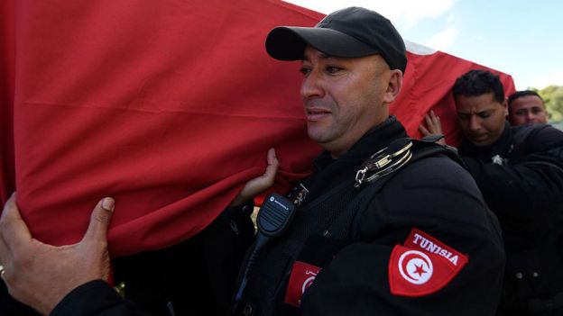 Un policía carga un ataud de una víctima de un atentado en Túnez.