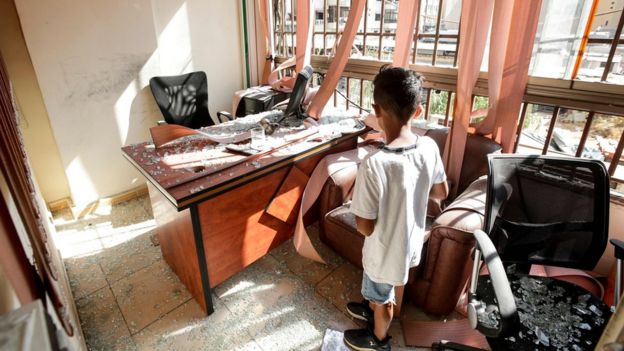 A boy stands amid broken glass inside a Hezbollah media office in southern Beirut, Lebanon (25 August 2019)
