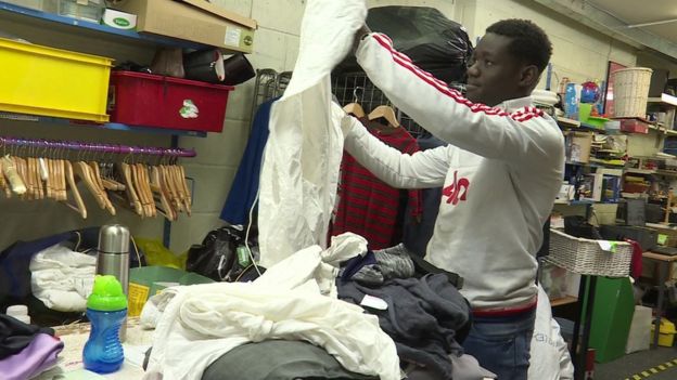 Un hombre revisa ropa en una tienda de Oxfam.